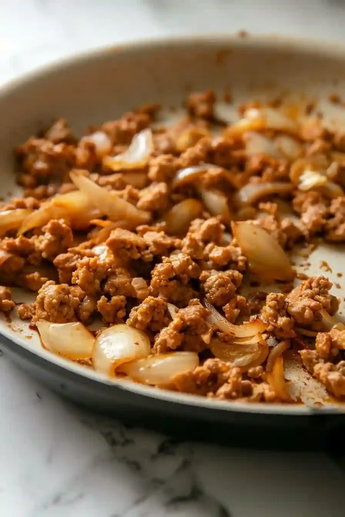 Ground turkey cooking in skillet turning golden with onions and garlic