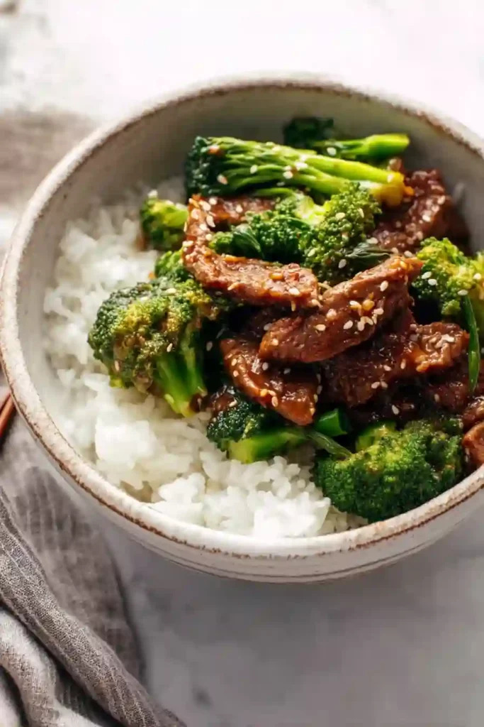 Sesame beef and broccoli plated with rice in a rustic bowl
