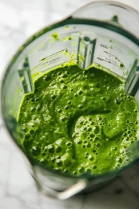 Green Smoothie with Cucumber, Ginger, and Pineapple 8 Deep green smoothie blending into a silky smooth texture inside blender jar