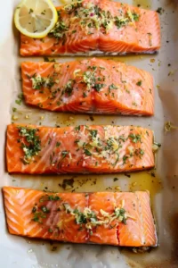 Healthy Sheet Pan Lemon-Herb Salmon with Asparagus Ready in 25 Min 11 Raw salmon fillets covered with lemon herb garlic marinade on baking sheet