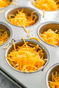 High-Protein Egg Bites for Meal Prep 5 Shredded cheese evenly distributed inside muffin cups before adding egg mixture