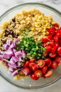 Quinoa Black Bean Salad with Lime Cumin Dressing 7 Warm quinoa mixed with colorful vegetables in a large bowl with dressing