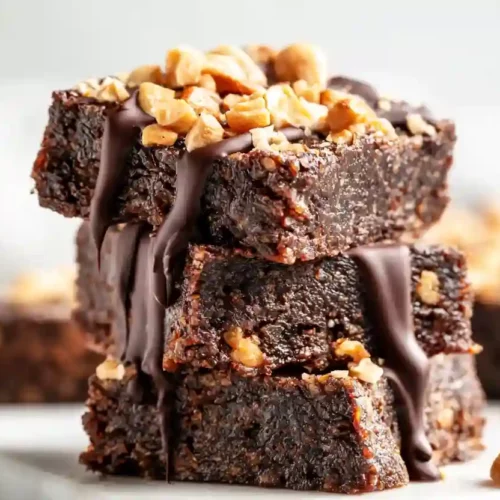 Crispy Peanut Butter Date Bars with Chocolate and Peanuts 2 Stack of crispy high-protein peanut butter date bars topped with chopped peanuts and melted chocolate drizzle