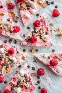 Raspberry Frozen Yogurt Bark 7 Fully frozen raspberry yogurt bark broken into rustic pieces with raspberries and toppings visible.