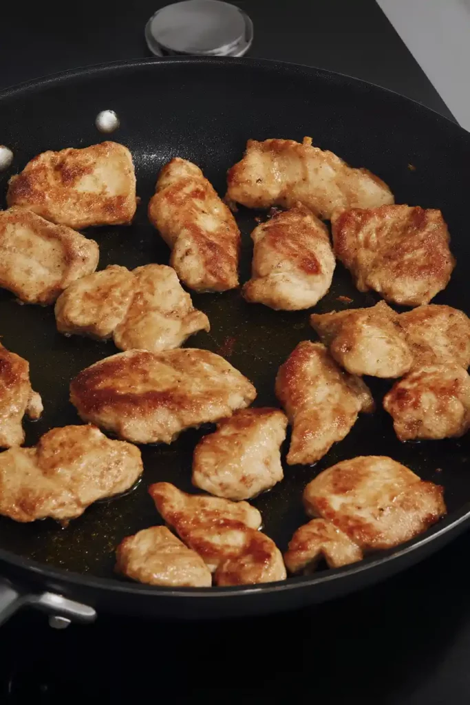 Meal Prep Honey Garlic Chicken Bowls 11 Golden brown chicken pieces cooking in a non-stick skillet with lightly crisped edges.