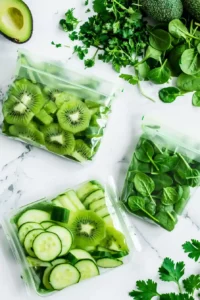 Green Protein Smoothie Bowl with Tropical Fruit 5 Ingredients for a green protein smoothie bowl arranged in freezer bags with kiwi, avocado, cucumber, spinach, and parsley.