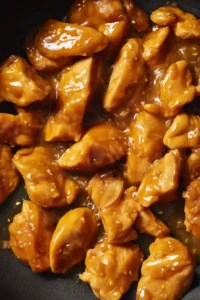 Meal Prep Honey Garlic Chicken Bowls 7 Golden chicken coated in a glossy honey garlic sauce inside a skillet.