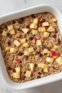 Apple cinnamon baked oatmeal mixture topped with diced apples before baking